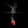 a strawberry dropped in water creating a splash
