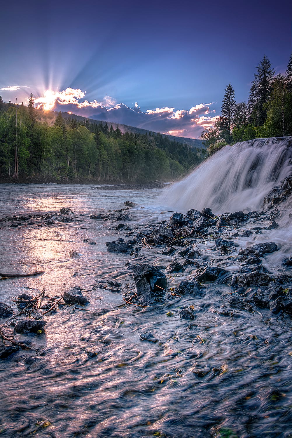Sunset over a river with a waterfall
