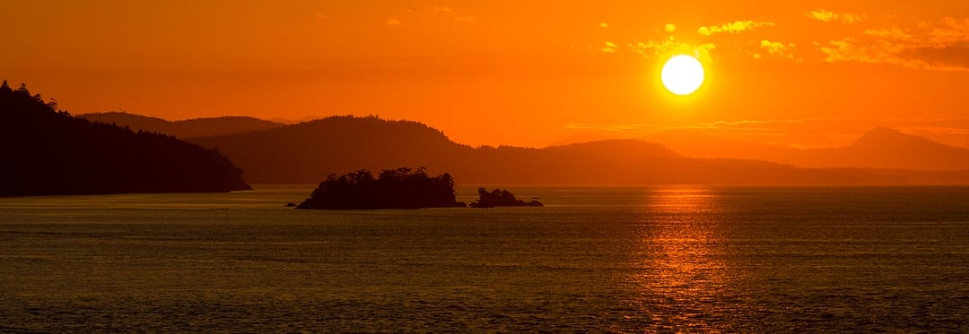 a sunset over small islands in a large body of water