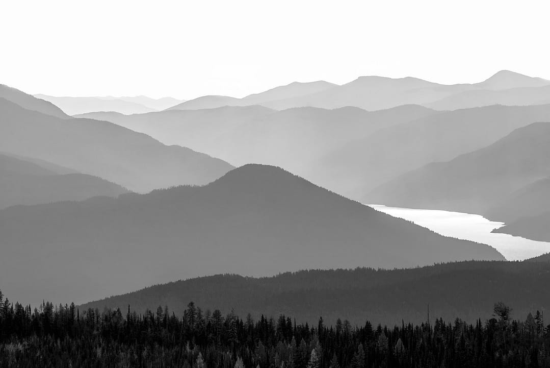 a black and white image of a mountain range with a lake