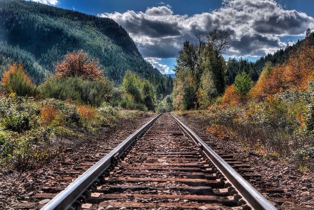 A railway in fall leading towards a mountain