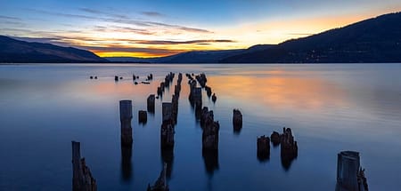 a sunrise over and abandoned dock in a body of water