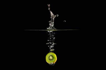 an kiwi dropped in water creating a splash