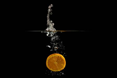 an orange dropped in water creating a splash
