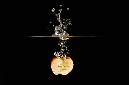 an apple dropped in water creating a splash