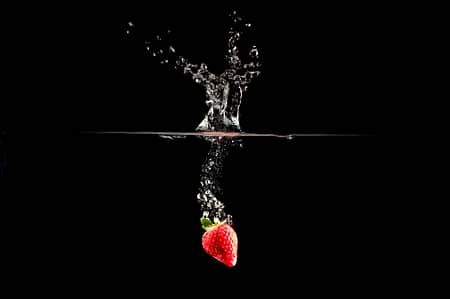 a strawberry dropped in water creating a splash