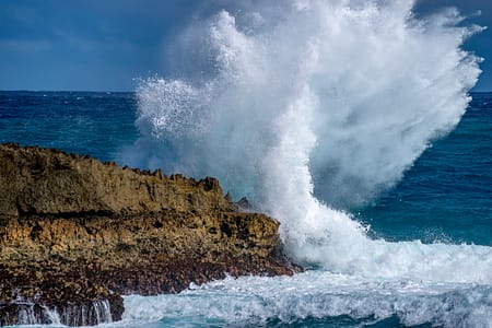 a large wave crashing on rocks in the pacific ocean