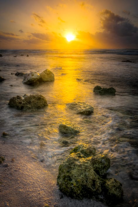 a rocky beach at sunrise with an ocean