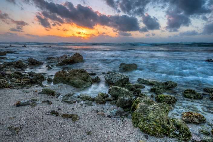 a sunrise with a rocky beach in the mayan riviera