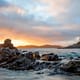 sunset with a rugged coastline over a body of water