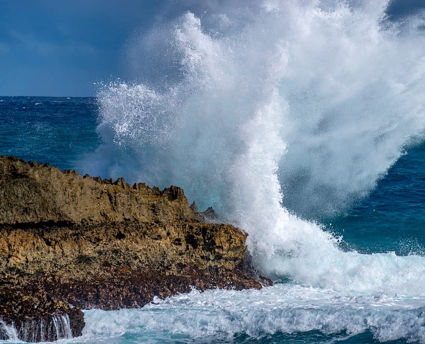a large wave crashing on rocks in the pacific ocean