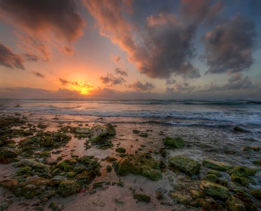 sunrise over a rocky beach and ocean in the Mayan Riviera